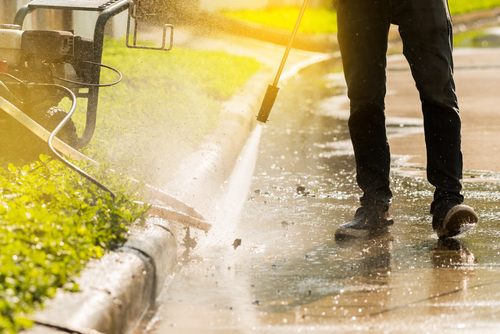 Man pressure washing the side of a pavement