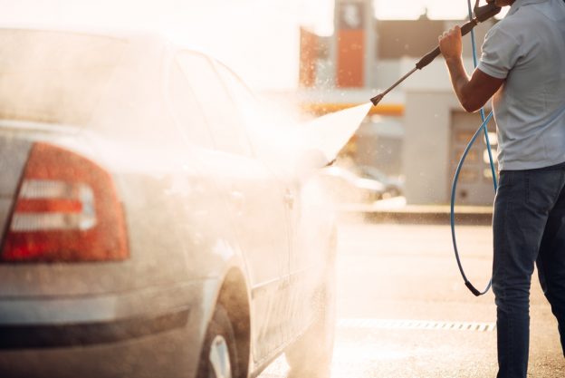 Man pressure washing his car