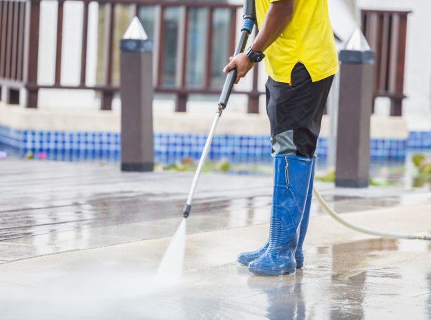 Man in wellies using a pressure washer on a floor