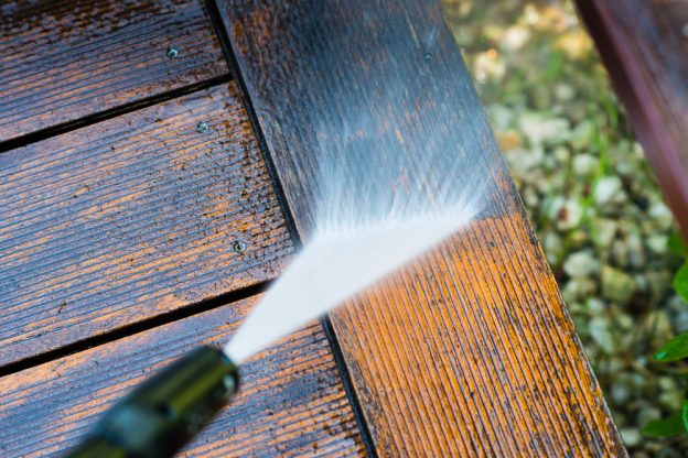 Pressure washing away dirt on a wooden panel