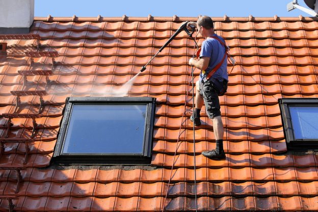 A man pressure washing a roof window