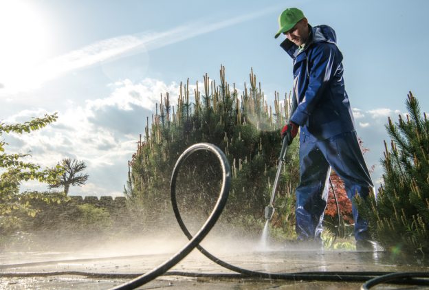 Man in hazmat suit using a pressure washer